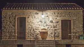 A stone building with two doors and a large vase on the ground.