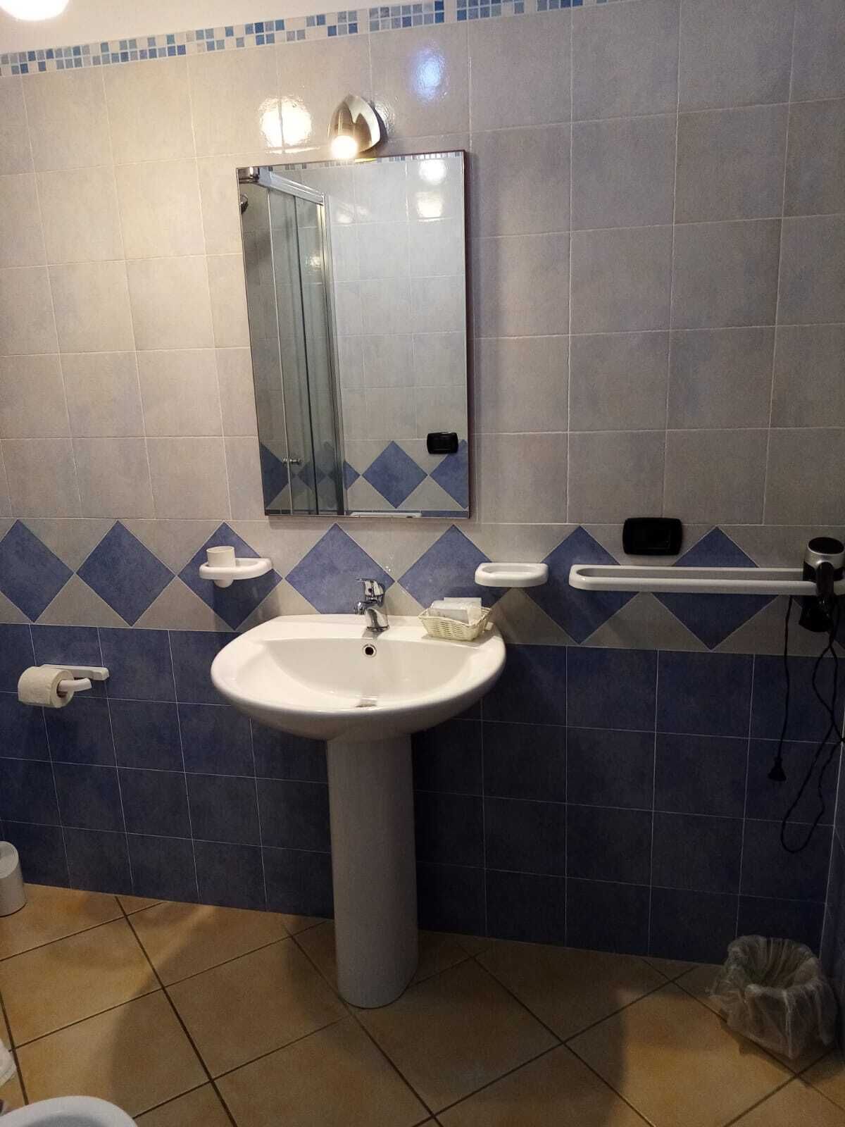 A bathroom with a white sink, a mirror, a towel rack, and a toilet.