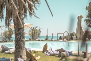 A poolside area with lounge chairs, umbrellas, and a view of the sea. - Riva del Sol Beach Resort (Santa Caterina dello Ionio)