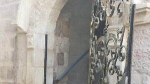 A metal gate with intricate designs, leading to a stone staircase with a stone wall on one side and a metal handrail on the other. - Beautiful appartment in city center (Jerusalem)