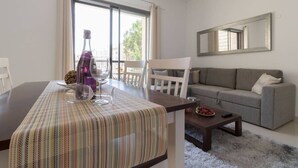 A modern living room with a dining table, a sofa, and a large window. - Beautiful appartment in city center (Jerusalem)