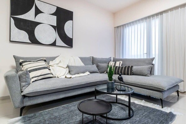 A modern living room with a grey sofa, a round coffee table, and a large abstract painting on the wall. - Haneviim Court Complex - 1 Bedroom (Multi-unit) (Jerusalem)