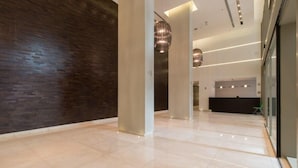A modern lobby with a polished floor, dark wooden wall, and contemporary lighting fixtures.