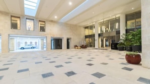 A spacious lobby with a tiled floor, large windows, and a car parked outside.