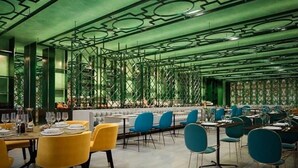 A restaurant with a green and white color scheme, featuring yellow and blue chairs, and a patterned ceiling.