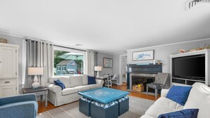 Ein modernes Wohnzimmer mit Kamin, Fernseher und Essbereich mit Tisch und Stühlen.