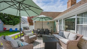 Eine Terrasses mit Korbmöbeln, einem Tisch und Sonnenschirmen.
