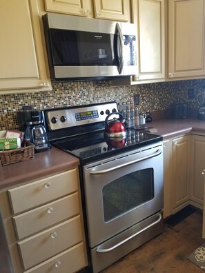 Fully equipped kitchen with stainless steel stove, microwave, and kettle, perfect for preparing meals.