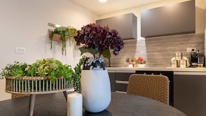 A modern kitchen with a dining table, a vase with flowers, and a hanging plant.