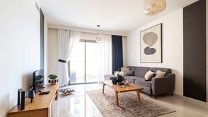 Una sala de estar moderna con un sofá gris, una mesa de centro de madera y un televisor sobre un mueble bajo de madera.