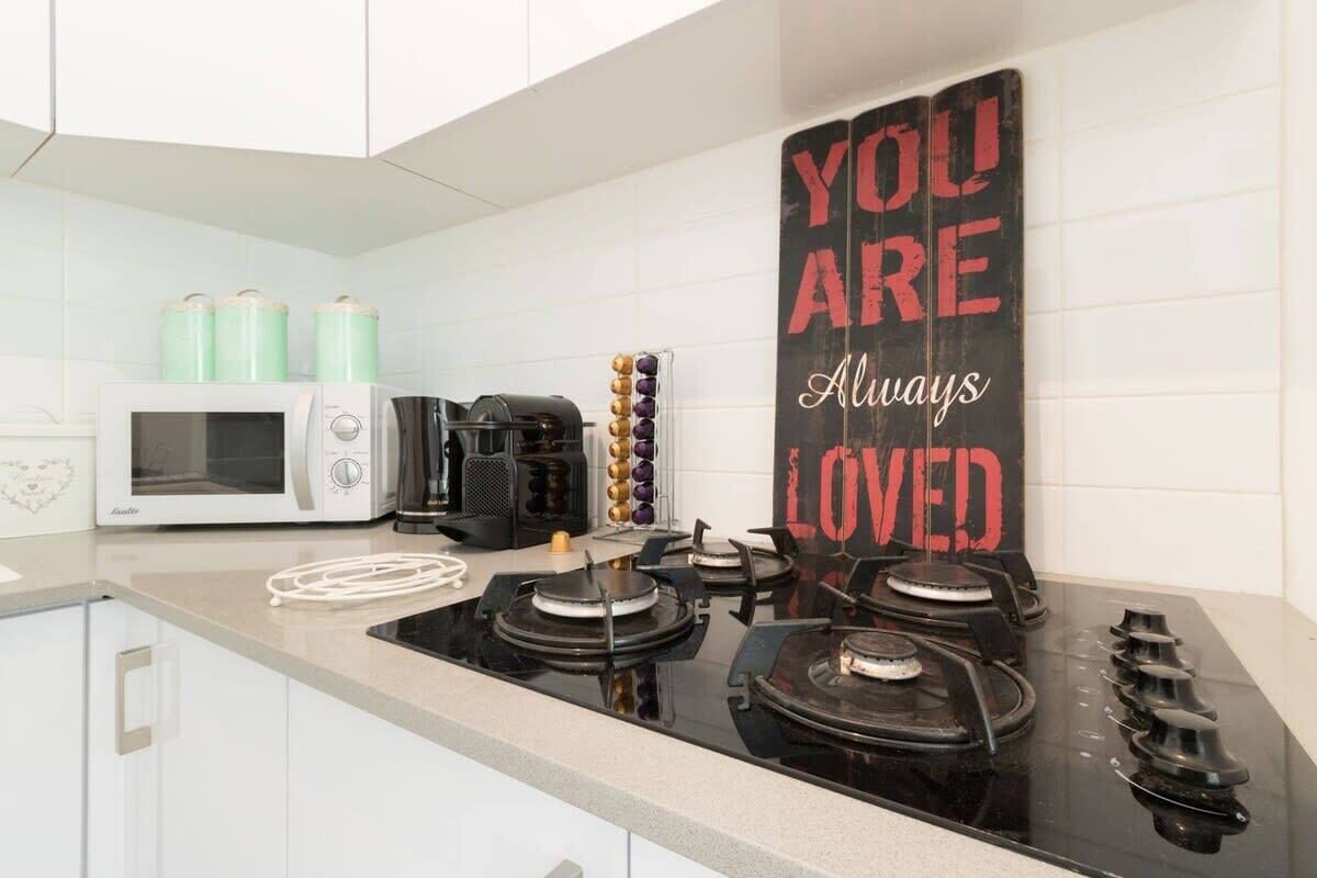 A kitchen with a gas stove, a coffee maker, and a microwave.