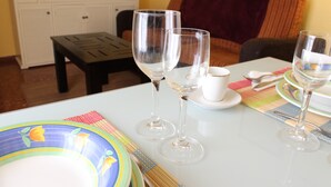 Una mesa de comedor con copas de vino, platos y cubiertos, en una habitación con un sofá y un aparador.