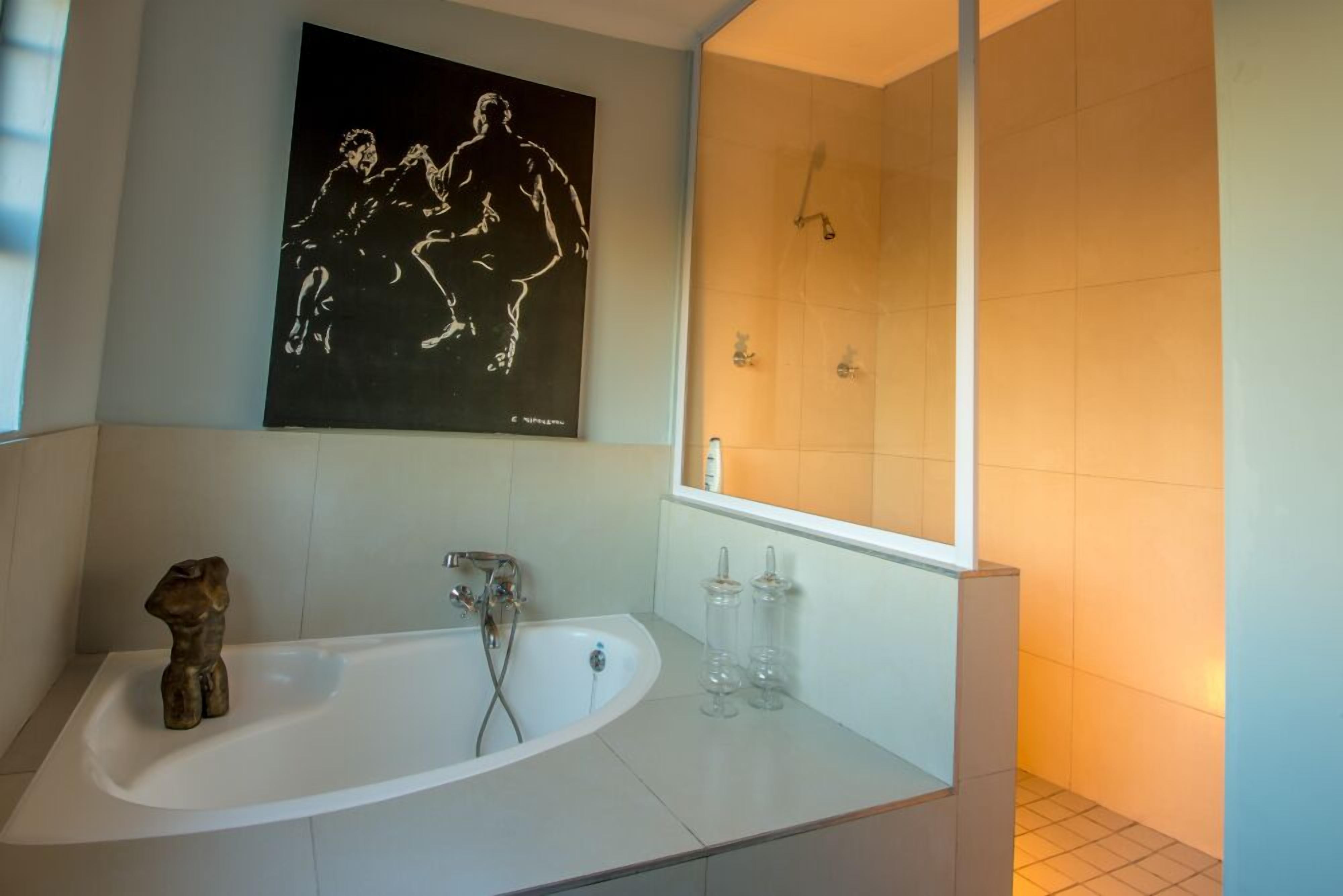 Un baño moderno con una bañera independiente, un espejo grande y una obra de arte en la pared.