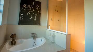 Un baño moderno con una bañera independiente, un espejo grande y una obra de arte en la pared.