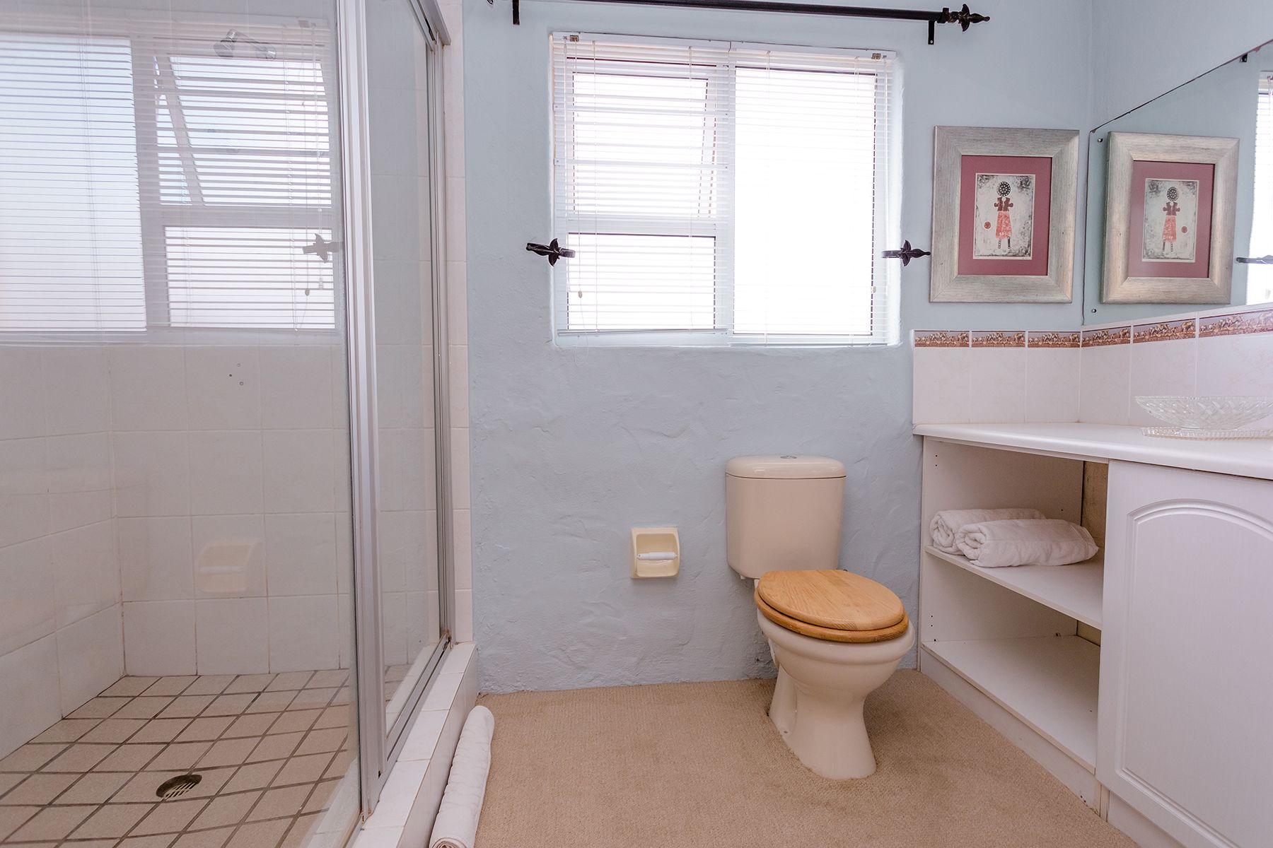 A bathroom with a shower, toilet, and a sink with a mirror.