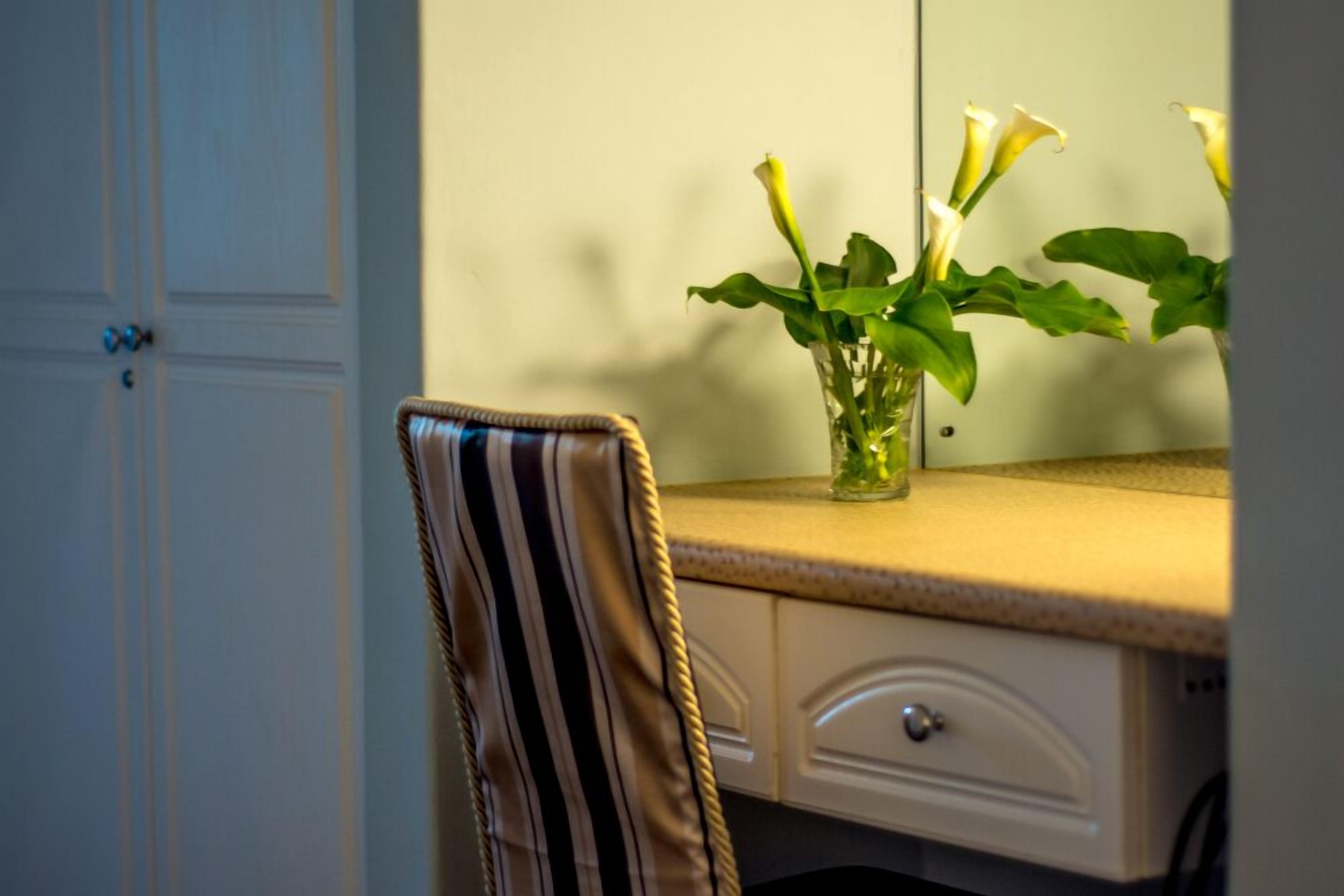 A room with a desk, a chair, and a vase with flowers.