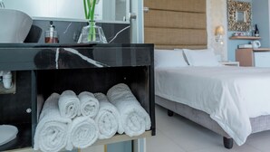 Una habitación de hotel moderna con una cama, un tocador con espejo y un perchero para toallas.