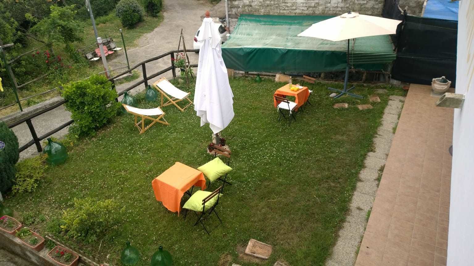 A garden with a table and chairs, a covered area, and a pathway.