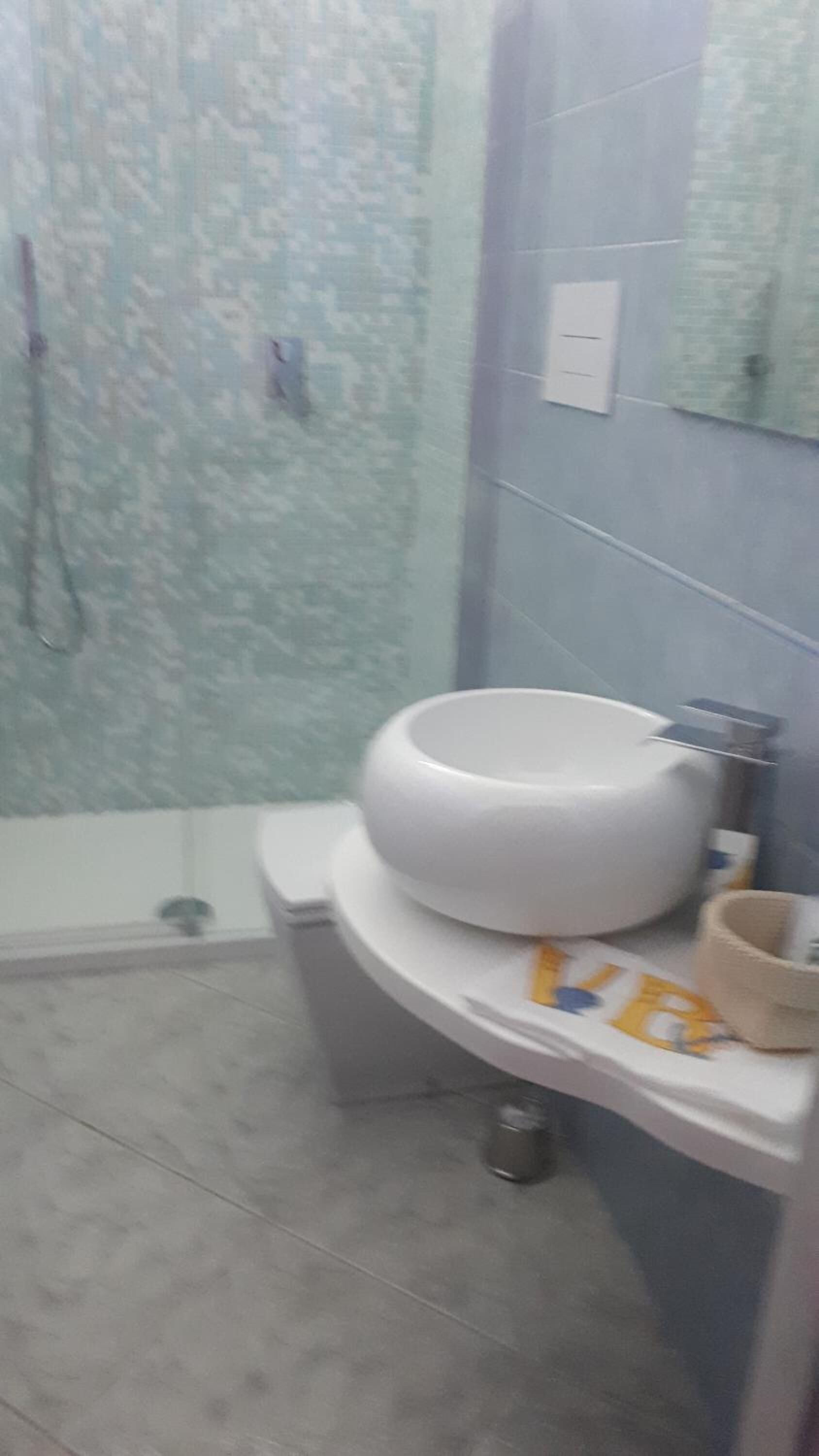Un baño con lavamanos blanco, un espejo y zona de ducha.