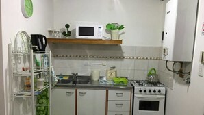 Une cuisine compacte équipée d’un four à micro-ondes, d’une cuisinière, d’un évier et de placards de rangement.