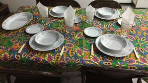 Une table à manger dressée avec des assiettes, des verres et des couverts, recouverte d’une nappe colorée.