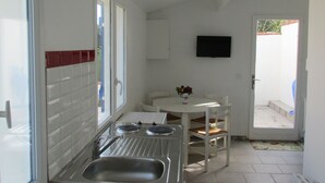 A compact kitchen with a sink, stove, and a small dining table with chairs. - 2 minutes walk from the beach (Pornic)