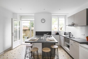 A modern kitchen with a central island, bar stools, and a view to the outside.