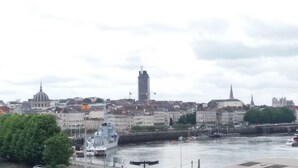 A cityscape with a prominent church, a tall modern building, and a river with boats. - MOSAIK, Charmant appartement Nantais (Nantes)