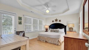 Ein Schlafzimmer mit Bett, Deckenventilator, Schreibtisch und Kommode.
