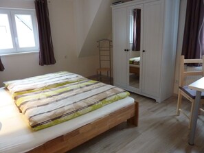 Ein Schlafzimmer mit Bett, Kleiderschrank, Stuhl und Fenster.