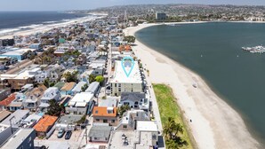 Luftaufnahme einer Küstenstadt mit Strand, Wohnhäusern und einem Yachthafen.
