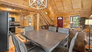 Eine geräumige Holzhütte mit großem Esstisch, integrierter Küche und einer gemütlichen Sitzecke.