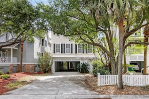 A two-story house with a covered front porch, a driveway, and a white picket fence.