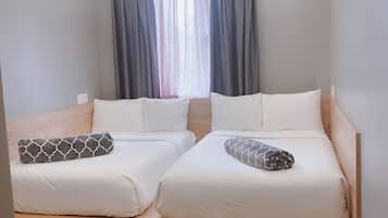 A modern hotel room with two beds, a wooden headboard, a patterned rug, and a large window with curtains.