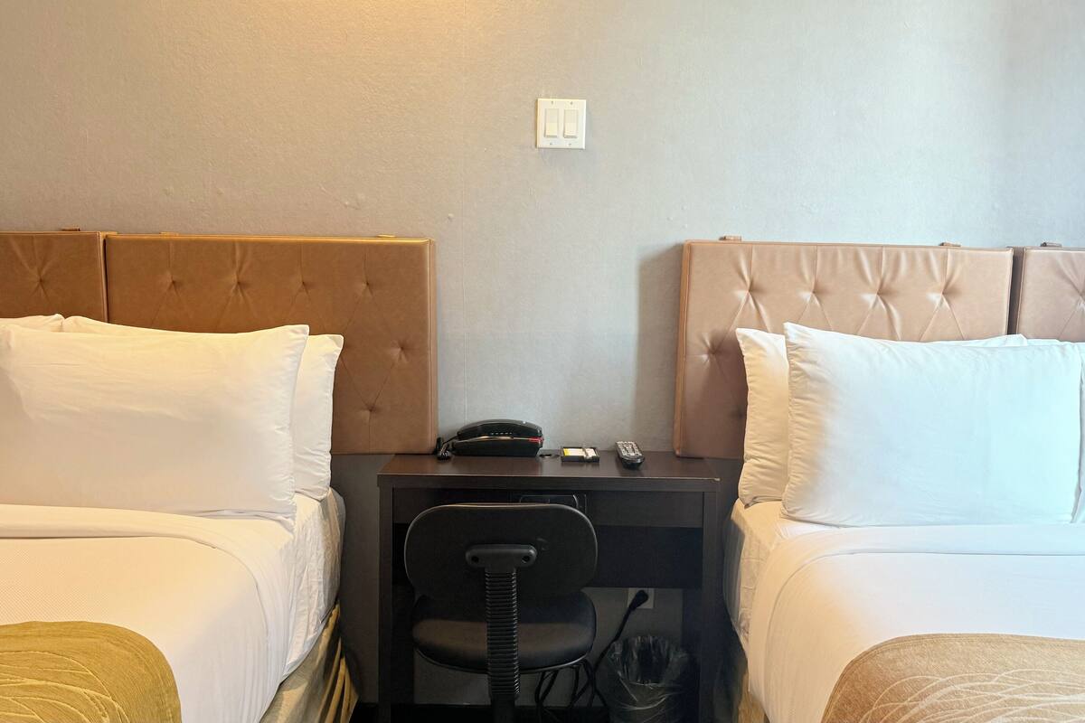 Habitación de hotel con dos camas, un escritorio y una silla.