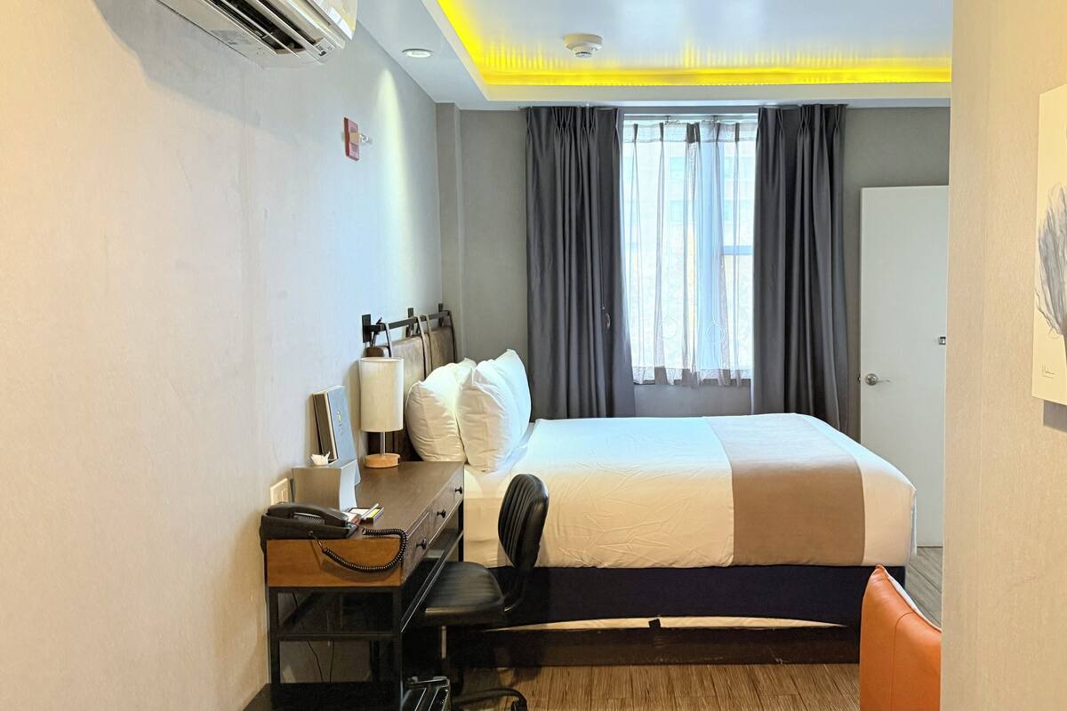 Habitación de hotel con cama, escritorio, silla y un cuadro en la pared.