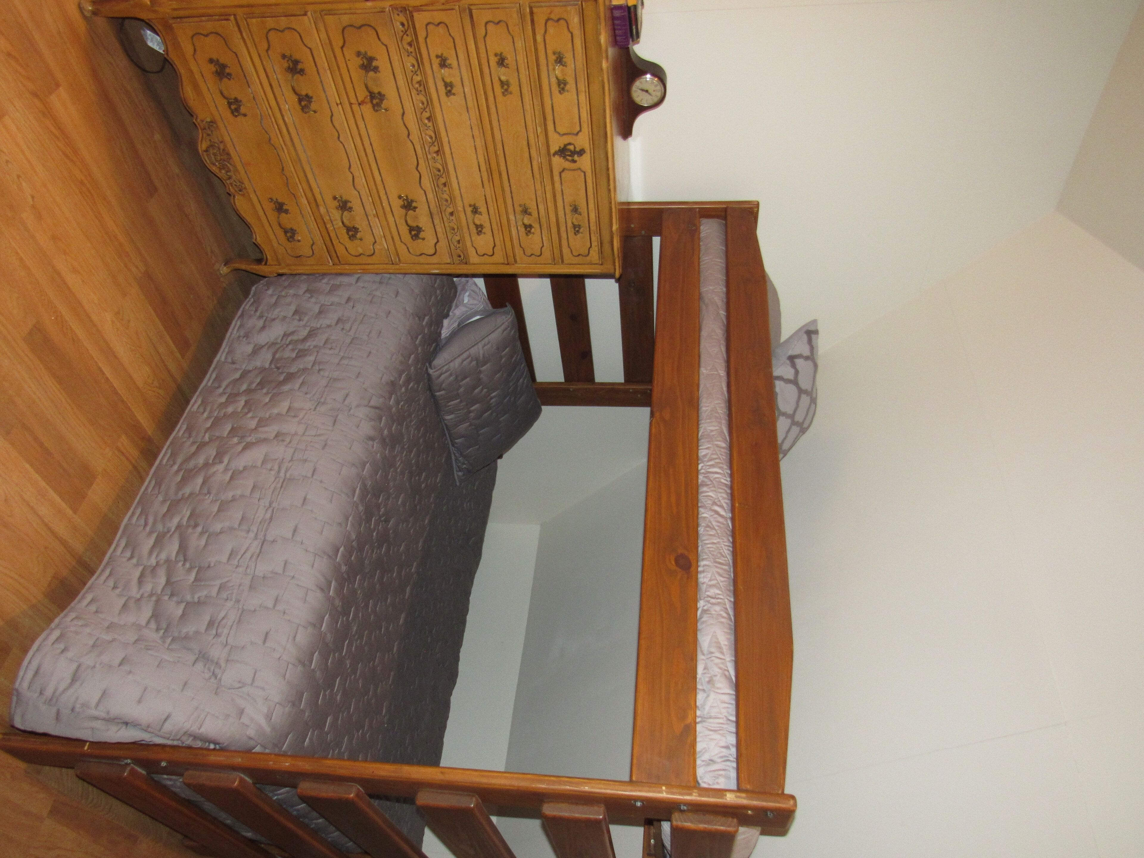 A bunk bed with a headboard and a wooden dresser with multiple drawers.