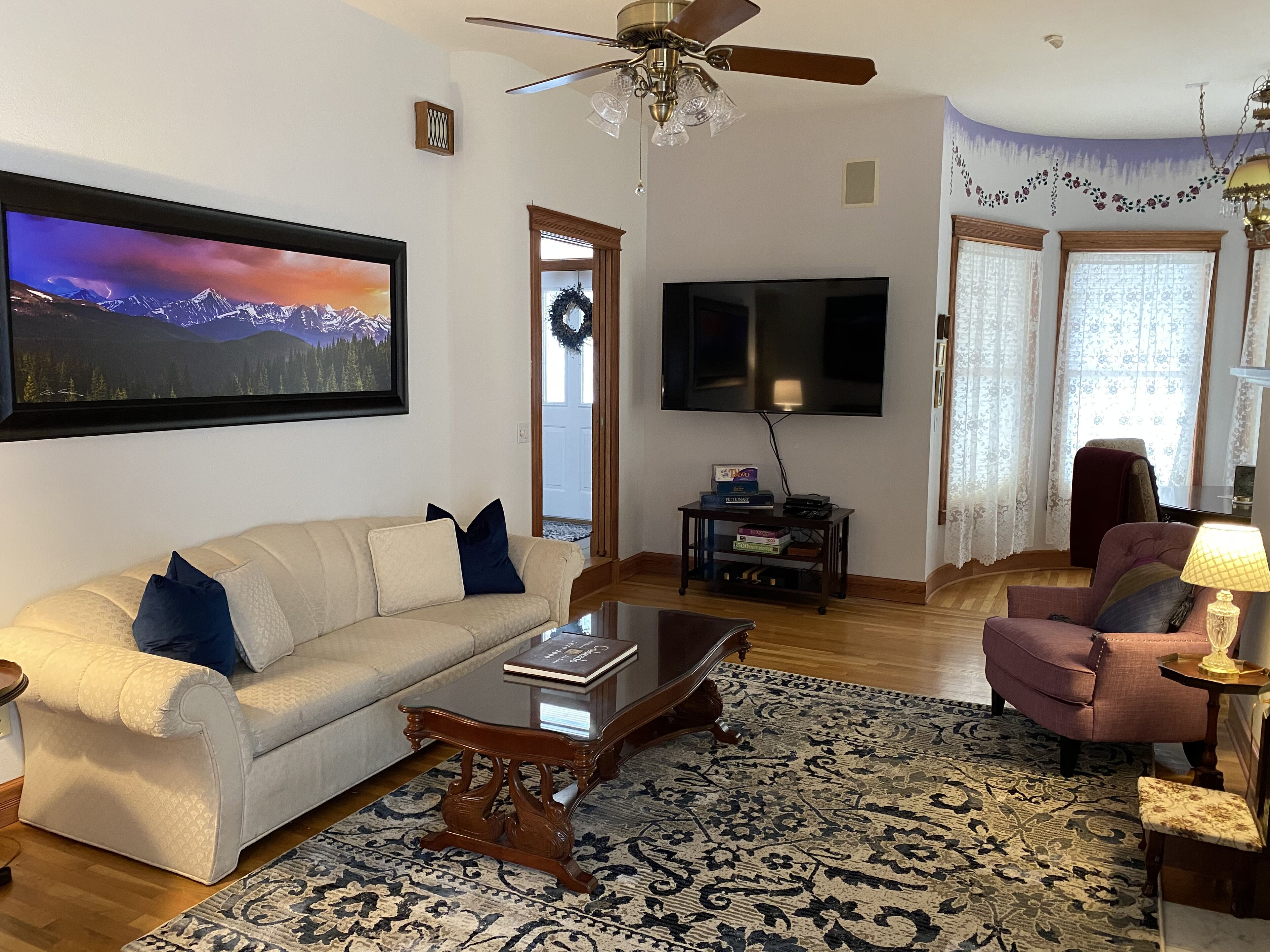 Una sala de estar con sofá, mesa de centro, alfombra, televisor y una silla.