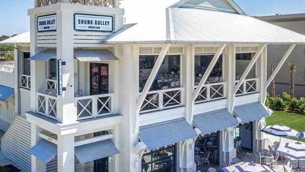 Un edificio blanco con un área de estar al aire libre techada y sombrillas.