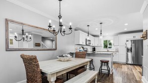Una cocina moderna con armarios blancos, un espejo grande y una araña.