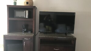 A kitchenette with a microwave, coffee maker, and a small cabinet. - Country West Motel (Rock Springs)