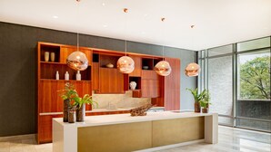 Un espace d’accueil moderne avec un comptoir de réception en bois, de nombreuses étagères et des luminaires sphériques suspendus.