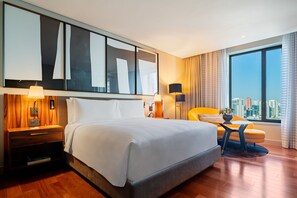 Une chambre d’hôtel avec un grand lit, un bureau, une chaise et une vue sur la ville.