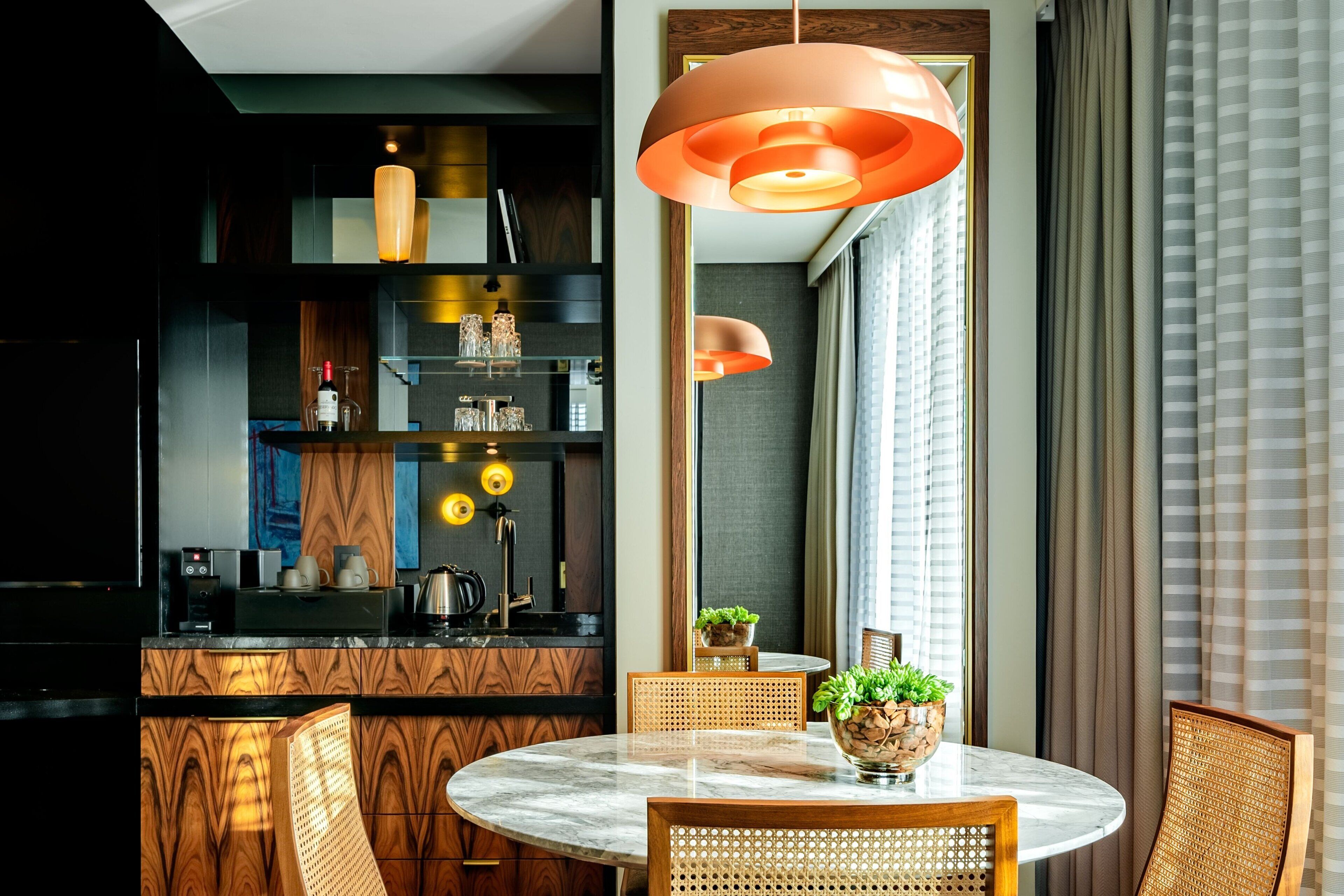Una cucina moderna con un tavolo rotondo, sedie in legno e una lampada a sospensione.