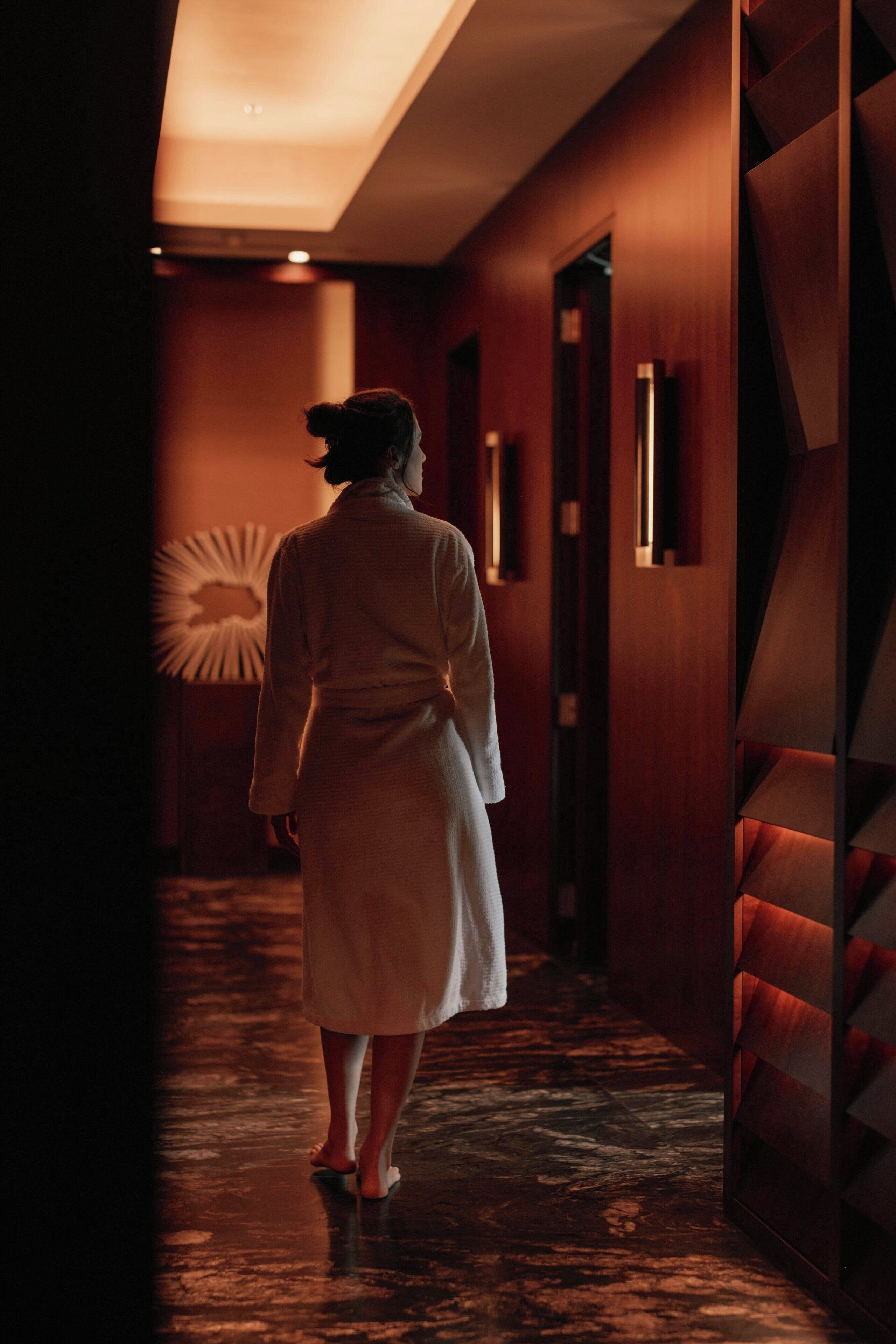 A person walking down a hallway with wooden walls and a patterned floor.