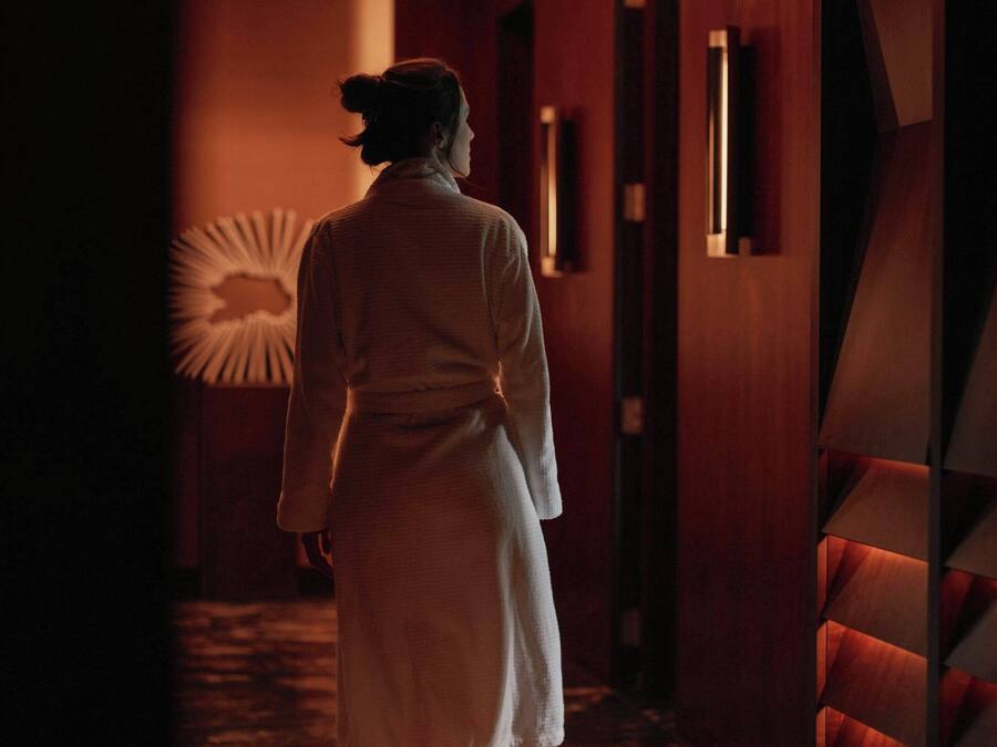 A person walking down a hallway with wooden walls and a patterned floor.