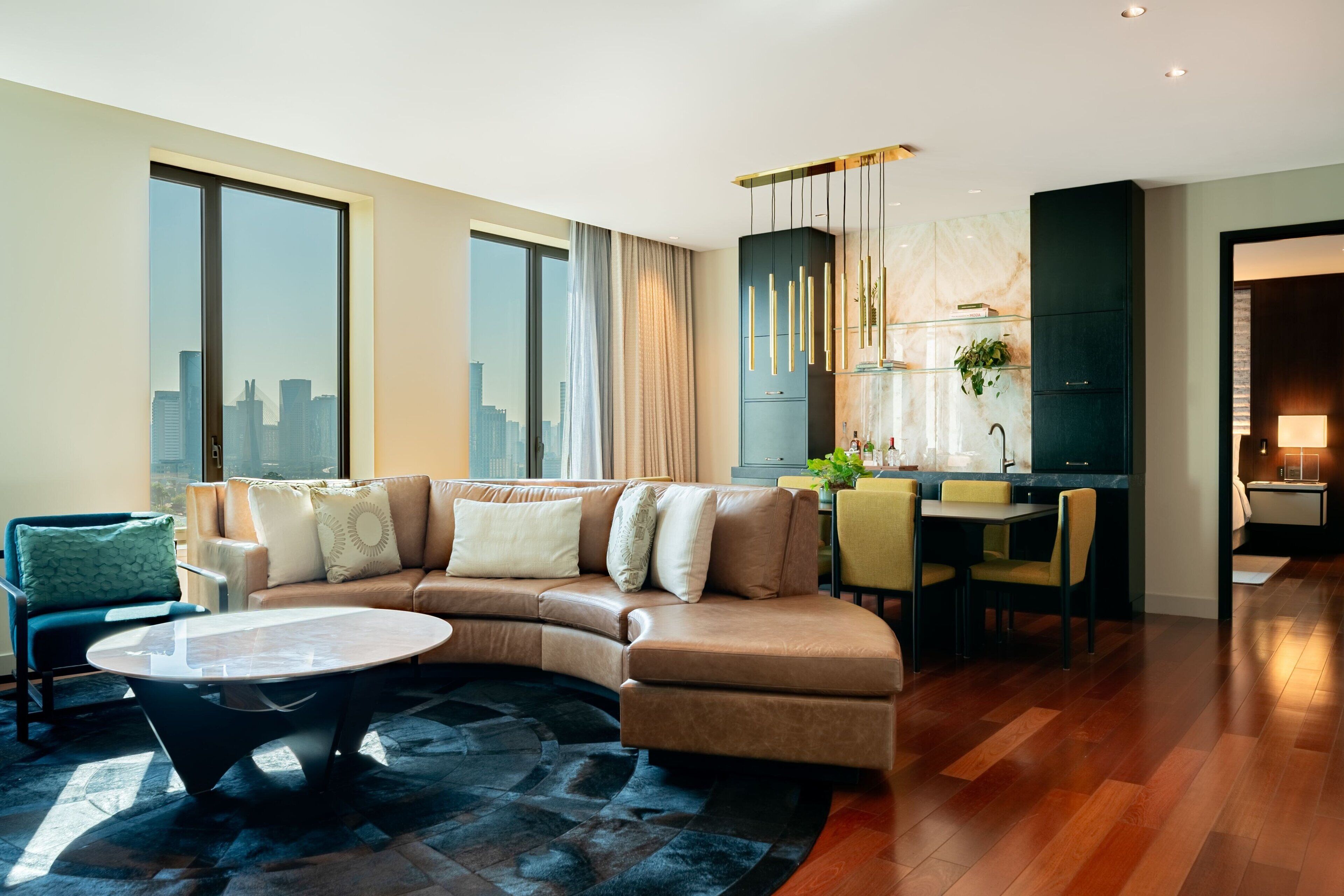 A modern living room with a curved sofa, a round coffee table, and a dining area with chairs.
