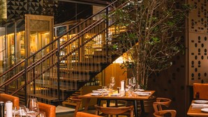 Un restaurant avec des tables et des chaises en bois, un escalier et un mur décoratif.