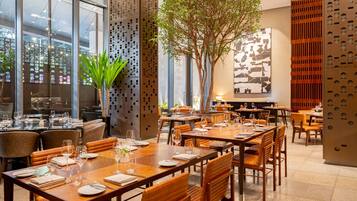 Un restaurante con varias mesas, sillas y un gran árbol en el centro.