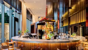 Eine moderne Bar mit einer gebogenen Theke, Barhocker und einer Auswahl an Flaschen und Gläsern.